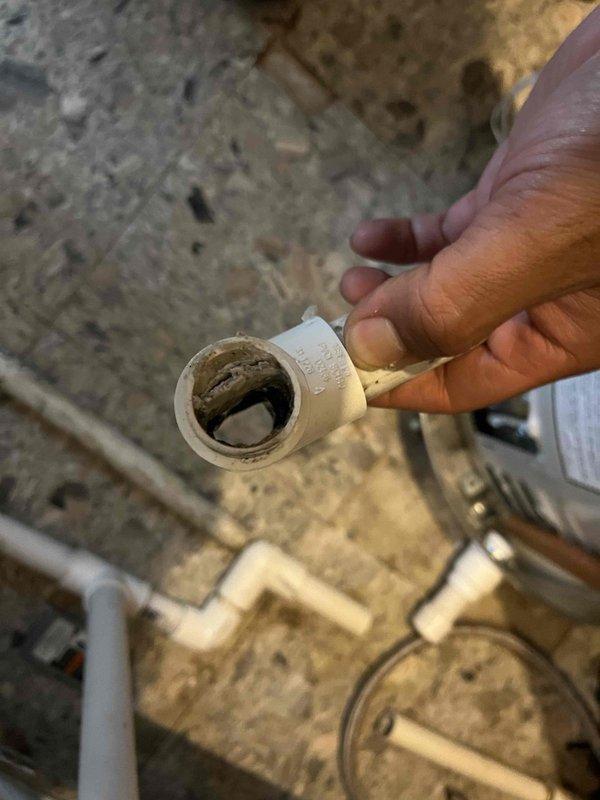 Responded to complaint of water heater cycling on and off with no hot water production in 50-year-old home. Upon inspection, discovered severe sediment and mineral buildup throughout plumbing system supply lines. Removed and examined affected pipe sections, revealing significant internal diameter restriction from accumulated deposits causing inadequate water flow to the recently installed tank water heater unit. The restricted flow was triggering the unit's safety controls, causing continuous cycling and preventing proper heating operation. Documented extensive buildup conditions with photographic evidence showing cross-sections of removed piping with heavy gray-brown mineral scaling and debris accumulation. Identified compromised water delivery system as root cause of heater malfunction rather than equipment failure.