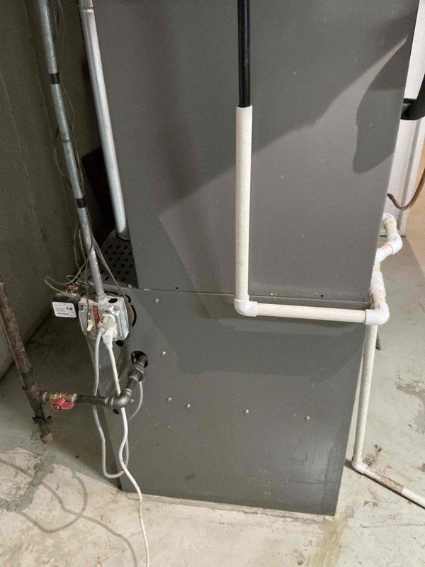 Performed comprehensive evaluation of residential HVAC system with confirmed evaporator coil refrigerant leak that had previously failed repair attempts. Assessed existing single-stage air conditioning unit and two-stage variable-speed heating system installed in basement mechanical room. Documented current system configuration including gray metal furnace cabinet, vertical ductwork with reflective insulation, PVC condensate drain lines, and electrical connections. Provided detailed estimate for complete A/C and coil replacement to resolve ongoing refrigerant leak issue and restore system reliability.