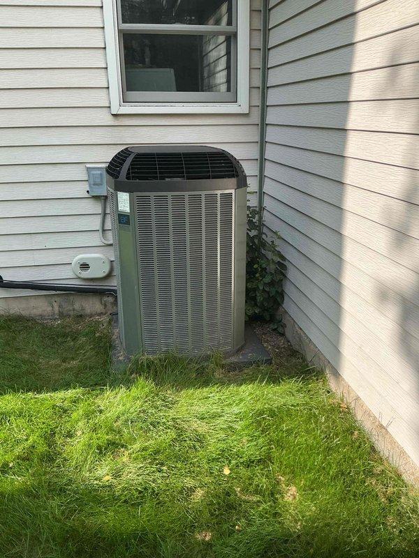 Responded to service call for air conditioning unit producing buzzing noise. Upon arrival, performed diagnostic inspection of outdoor condensing unit and associated electrical components. Inspected condenser fan motor, contactor, and capacitor for signs of failure or abnormal operation. Verified refrigerant line connections and checked for any loose mounting hardware or debris interference that could cause unusual sounds. Unit appeared operational at time of inspection with no active buzzing present during visit. Documented equipment condition with photos of outdoor unit installation and indoor basement mechanical area showing associated piping and drainage systems.