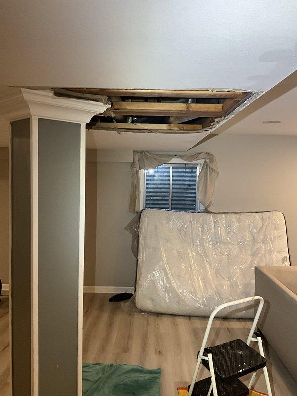 Responded to emergency call for burst pipe in basement. Upon arrival, found that ceiling had already been opened to expose the damaged plumbing line. Assessed copper supply line with compromised joint connection in ceiling cavity above living space. Customer had protected furniture with plastic sheeting in affected room. Repaired burst pipe section, replaced damaged fittings, and secured all connections with proper sealing. Verified system integrity through pressure testing to ensure no additional leaks were present in the exposed plumbing runs. All water flow restored to normal operation.