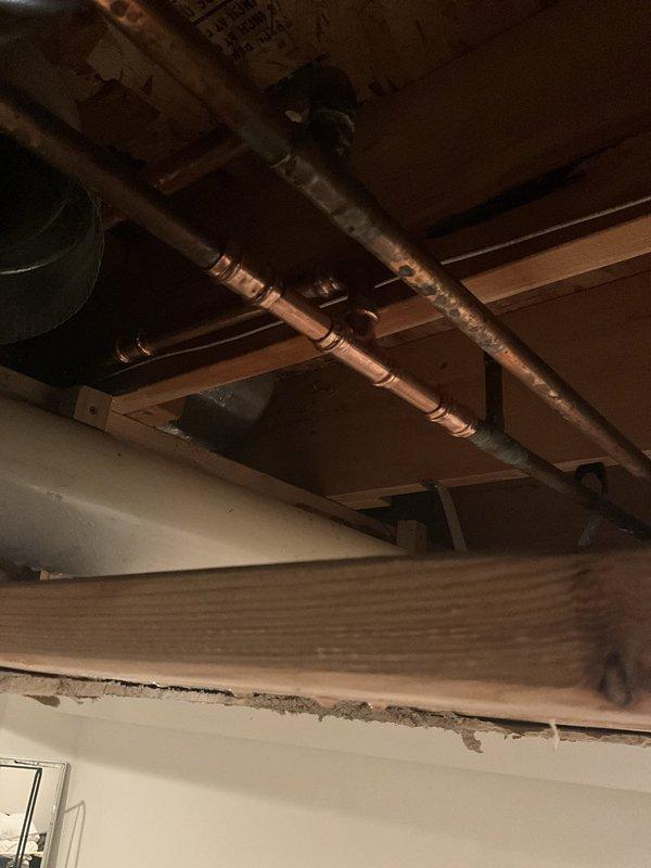 Responded to emergency call for burst pipe in basement. Upon arrival, found that ceiling had already been opened to expose the damaged plumbing line. Assessed copper supply line with compromised joint connection in ceiling cavity above living space. Customer had protected furniture with plastic sheeting in affected room. Repaired burst pipe section, replaced damaged fittings, and secured all connections with proper sealing. Verified system integrity through pressure testing to ensure no additional leaks were present in the exposed plumbing runs. All water flow restored to normal operation.