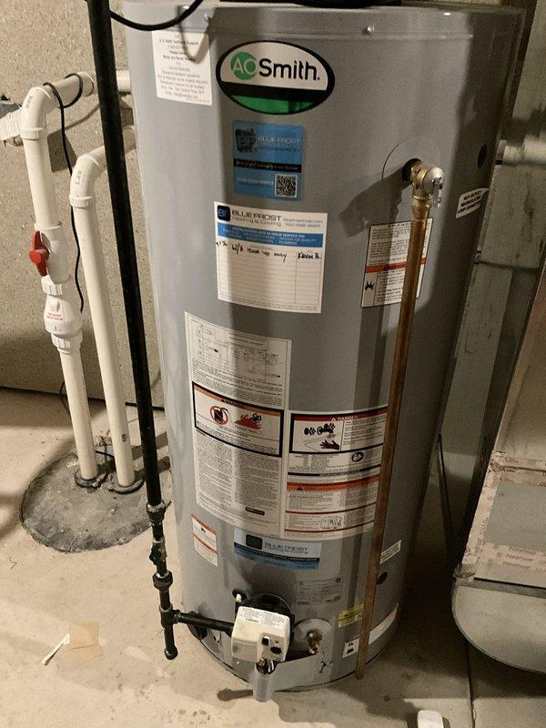 Completed comprehensive tune-up and maintenance service on AO Smith tanked water heater in residential basement utility room. Performed full system inspection including verification of pressure relief valve operation, examination of all plumbing connections and fittings, assessment of venting components, and visual inspection of tank condition. Checked gas line connections, tested safety controls, and verified proper clearances around unit. All components found to be functioning within normal operating parameters with no immediate concerns identified. Unit properly labeled with current safety and warranty information, and installation appears to meet code requirements with appropriate piping configurations in place.