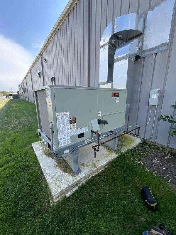 Responded to non-member service call for commercial ground-mounted package unit reported as non-operational since previous Wednesday. Upon arrival, inspected exterior-mounted HVAC unit with upward-discharge ductwork configuration. Performed diagnostic assessment of condenser fan assembly and motor hub, examining protective grille and blade operation. Evaluated electrical disconnect, refrigerant line connections, and overall unit condition. Documented equipment status with photos showing fan assembly components and complete unit installation on concrete pad. Unit operational status verified and customer advised of findings.