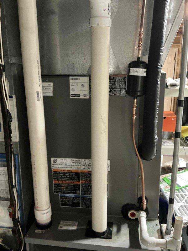 Completed full residential air conditioning system replacement consisting of outdoor condensing unit and indoor air handler with evaporator coil. Installed new Lennox 13 SEER split system in basement mechanical room with outdoor unit positioned on exterior wall. Ran new refrigerant lines with proper insulation and installed filter drier in copper line set. Replaced electrical whip and upgraded to 40 amp circuit breaker to meet equipment specifications. Replaced outdoor disconnect as required for proper electrical service. Connected condensate drainage using white PVC piping routed vertically along air handler. Secured all refrigerant connections with brazed joints and pressure tested system. Mounted air handler on drain pan and connected to existing ductwork. Commissioned system with full operational testing to verify proper airflow, refrigerant charge, and electrical connections. Unit operating within manufacturer specifications upon completion.