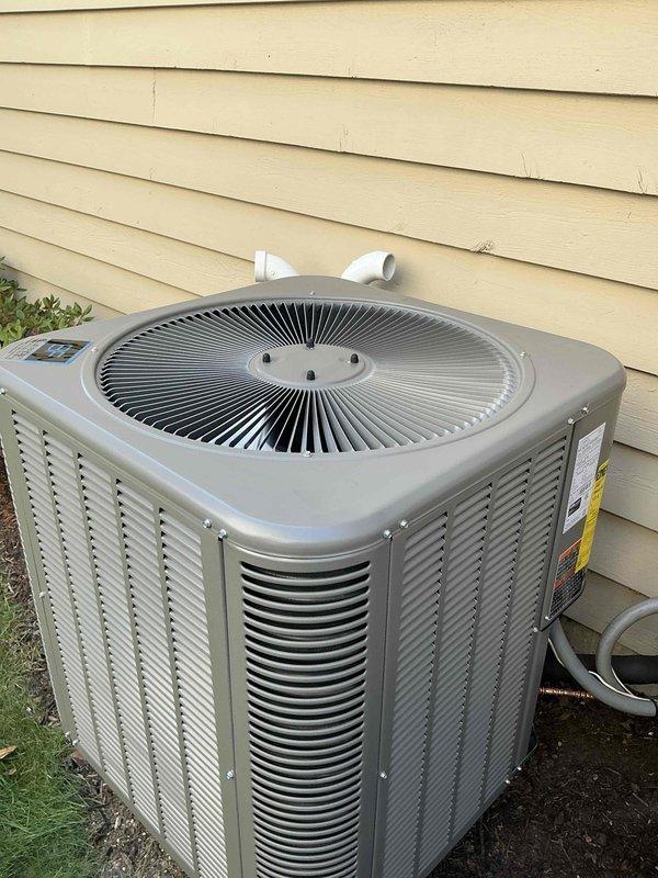 Completed full residential air conditioning system replacement consisting of outdoor condensing unit and indoor air handler with evaporator coil. Installed new Lennox 13 SEER split system in basement mechanical room with outdoor unit positioned on exterior wall. Ran new refrigerant lines with proper insulation and installed filter drier in copper line set. Replaced electrical whip and upgraded to 40 amp circuit breaker to meet equipment specifications. Replaced outdoor disconnect as required for proper electrical service. Connected condensate drainage using white PVC piping routed vertically along air handler. Secured all refrigerant connections with brazed joints and pressure tested system. Mounted air handler on drain pan and connected to existing ductwork. Commissioned system with full operational testing to verify proper airflow, refrigerant charge, and electrical connections. Unit operating within manufacturer specifications upon completion.