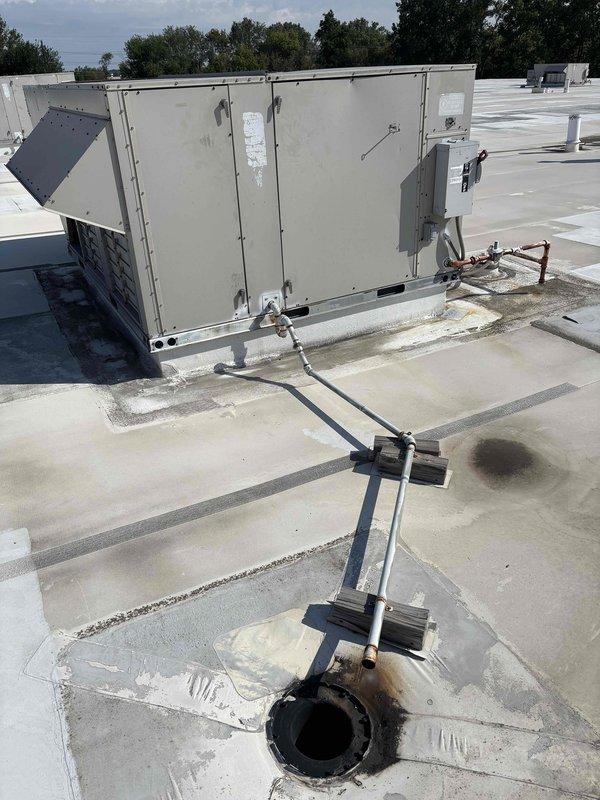 Completed scheduled BFMA preventive maintenance on commercial rooftop unit, performing comprehensive tune-up service that included replacement of nine filters across the RTU system. Documented existing rooftop conditions including rust staining around roof penetrations and general equipment positioning during routine filter change service.