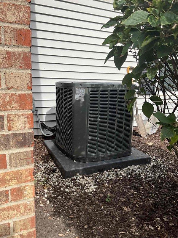 Leveled outdoor AC condenser unit and repositioned on composite pad to ensure proper drainage and optimal system performance. Unit was assessed for stability and adjusted to manufacturer specifications, with surrounding area cleared and mulch redistributed for adequate airflow around the condenser.
