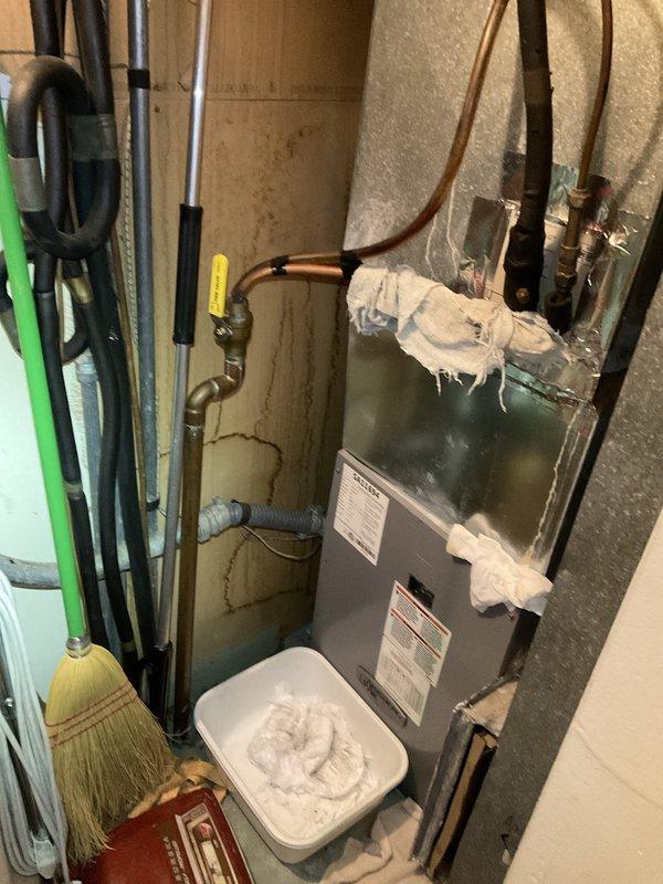 Responded to no cooling complaint on 20-year-old residential air conditioning system. Upon arrival, performed diagnostic evaluation of HVAC equipment located in basement utility area. Inspected furnace/air handler unit, refrigerant lines, electrical connections, and thermostat operation. Documented existing system conditions including copper refrigerant piping with brass fittings, electrical wiring, and wall-mounted programmable thermostat. System assessed and findings photographed for service records.