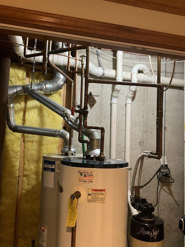 Conducted on-site evaluation for water heater replacement and sump pump system installation in basement utility area. Assessed existing dual 40-gallon water heater configuration and provided estimate for consolidation to single 50-gallon unit, including necessary plumbing modifications to accommodate updated capacity and connections to existing copper and PVC supply lines. Evaluated current sump pump system and provided quote for primary sump pump replacement along with battery-powered backup system installation to ensure flood protection redundancy. Documented existing mechanical room layout, including proximity to furnace, HVAC ductwork, water softener system, and available clearances for equipment access and code compliance.