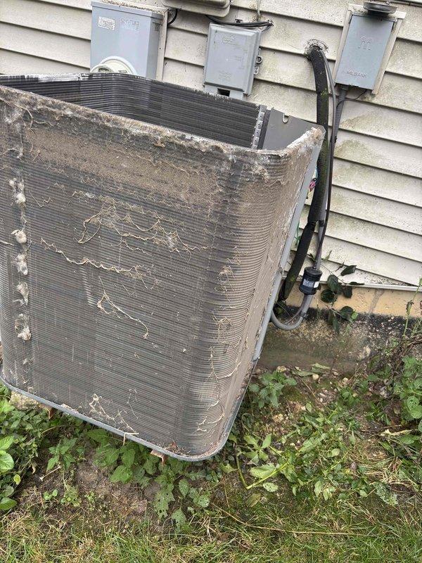 Completed comprehensive BFMA tune-up service on outdoor air conditioning condenser unit aged 4+ years. Unit exhibited heavy accumulation of dirt, dust, and debris on exterior panels, filter covers, and aluminum cooling fins, with visible damage to fin spacing and compression in several areas. Performed thorough cleaning of condenser coils, straightened bent fins to restore proper airflow, removed caked-on debris from exterior surfaces and filter components, and cleared vegetation growth from base perimeter. Inspected electrical connections at service panels and conduit runs, verified proper operation of all components, and restored unit to optimal efficiency standards. System now operating within manufacturer specifications following maintenance protocol.