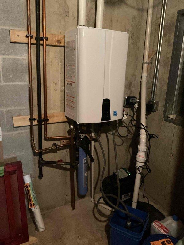 Completed comprehensive BFMA tune-up service on an 8-year-old tankless water heater system in residential basement utility area. Performed full maintenance protocol including inspection of all copper supply lines, mounting brackets, electrical connections, and plumbing components with brass shut-off valves. Verified proper operation of Energy Star rated unit, checked digital display functionality, examined water treatment system connections, and confirmed all safety equipment including fire suppression is properly positioned and accessible.