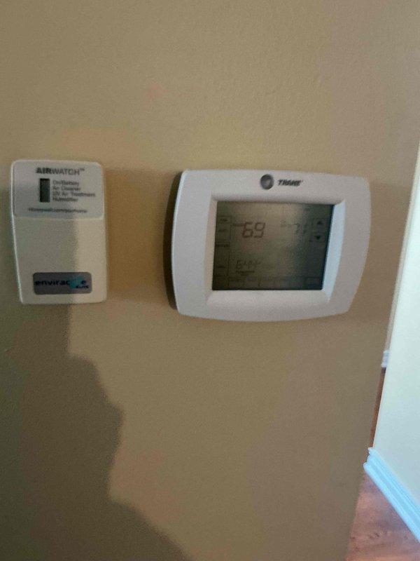 Completed comprehensive BFMA tune-up service including both air conditioning and furnace systems for one-year-old equipment. Performed standard maintenance procedures on Trane HVAC system, verified thermostat operation and settings, and confirmed AirWatch environmental monitoring system functionality. Documented exterior condenser unit condition, noting weathering on top panel surface, and captured interior equipment status with photographic records for maintenance history.