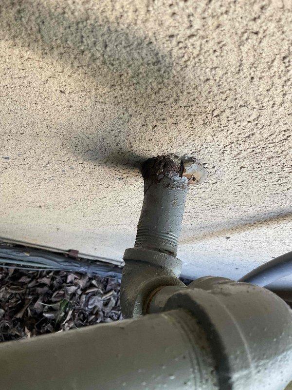 Identified and marked a small refrigerant leak on the line set where it penetrates the building exterior. Documented the leak location with photographs showing the affected pipe fitting and surrounding area. Recommended performing a complete system pressure check to verify integrity of all refrigerant lines and connections before proceeding with repairs.