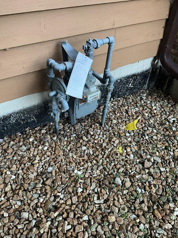 Responded to service call to assess status of water and gas lines serving an old pool. Conducted thorough visual inspection of exterior utility connections and documented findings with photographs. Located and examined natural gas meter installation with blue-painted piping configuration and pressure regulator mounted on building exterior, as well as secondary utility connections at grade level near mechanical equipment. Verified gas service line remains active with proper metering in place. Unable to definitively determine water line status from visual inspection alone; additional investigation would be required to trace and test water supply lines to former pool location.