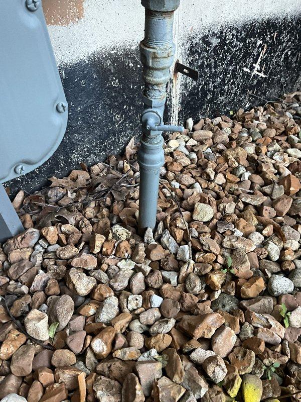 Responded to service call to assess status of water and gas lines serving an old pool. Conducted thorough visual inspection of exterior utility connections and documented findings with photographs. Located and examined natural gas meter installation with blue-painted piping configuration and pressure regulator mounted on building exterior, as well as secondary utility connections at grade level near mechanical equipment. Verified gas service line remains active with proper metering in place. Unable to definitively determine water line status from visual inspection alone; additional investigation would be required to trace and test water supply lines to former pool location.