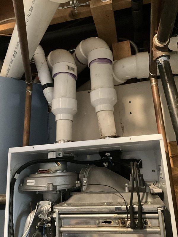 Responded to emergency no hot water call and inspected tankless water heater unit with visible burn mark on exterior casing and missing sight glass window. Diagnosed system failure affecting whole house hot water supply. Assessed mechanical components, plumbing connections including copper supply lines and PVC venting, and verified unit was inoperable due to compromised combustion chamber integrity indicated by external thermal damage and missing observation port.