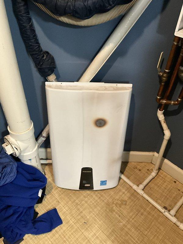 Responded to emergency no hot water call and inspected tankless water heater unit with visible burn mark on exterior casing and missing sight glass window. Diagnosed system failure affecting whole house hot water supply. Assessed mechanical components, plumbing connections including copper supply lines and PVC venting, and verified unit was inoperable due to compromised combustion chamber integrity indicated by external thermal damage and missing observation port.