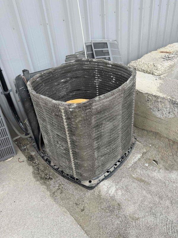 Responded to commercial AC service call for non-cooling issue in shop unit. Upon arrival, found outdoor condenser unit in severely deteriorated condition with outer casing completely removed, exposing internal components to elements. Coil assembly heavily contaminated with thick layers of dirt, dust, and debris accumulation, restricting airflow and significantly reducing heat transfer efficiency. Inspected electrical disconnect switch, which showed signs of age with oxidation present on brass terminals and wear on housing. Unit's exposed condition indicated prolonged operation without proper protective enclosure, resulting in accelerated component degradation and compromised system performance.