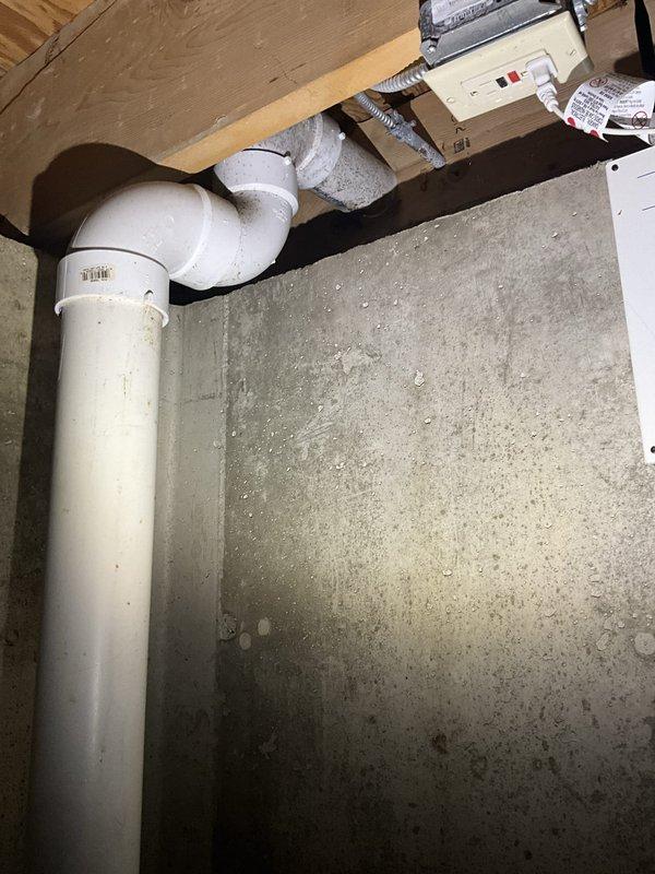 Performed complimentary sump pump inspection. Verified proper operation of sump pump system, including pit assembly with black circular cover, PVC discharge piping with rubber coupling and metal clamp connections, and secondary drainage line. Inspected vertical discharge pipe routing along foundation wall with elbow joint connection. All components found to be functioning properly with adequate water level in pit and secure pipe connections. System operational and ready for continued service.