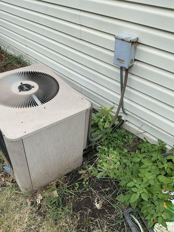 Completed HVAC estimate for full system replacement on residential property with 17+ year old equipment. Client's existing furnace has a damaged heat exchanger requiring immediate replacement for safety concerns. Evaluated outdoor condensing unit positioned against house exterior, noting significant age-related deterioration, weathering, and accumulation of dirt and debris on surfaces. Unit shows clear signs of extended service life with worn components and requires replacement along with indoor coil to ensure proper system matching and efficiency. Documented existing electrical disconnect box and conduit configuration for replacement planning. Provided comprehensive estimate for new furnace and air conditioning system installation to address failed heat exchanger and aging equipment concerns.