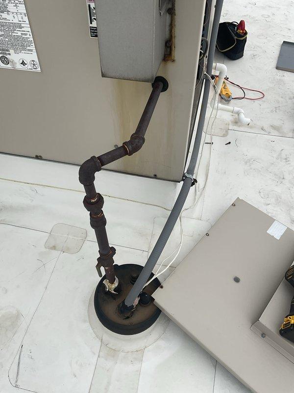 Responded to commercial no cooling call for rooftop unit. Upon arrival, accessed RTU via ladder and performed diagnostic inspection. Found condenser fan motor inoperative with visible signs of weathering, corrosion, and age-related deterioration on fan guard and motor assembly. Thermostat was powered but unable to initiate cooling mode due to failed outdoor unit operation. Inspected refrigerant piping connections, electrical components, and condensing unit assembly. Documented equipment condition with photos showing significant oxidation on fan motor hub and protective wire guard, indicating prolonged exposure to outdoor elements and end-of-service-life condition requiring replacement.