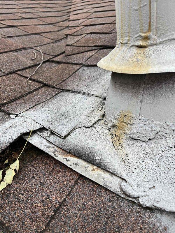 Responded to report of water leaking from residential HVAC unit. Upon inspection, identified the source as roof penetration failure at the flue pipe rather than the HVAC system itself. The rubber boot flashing surrounding the metal vent stack showed severe deterioration with torn sections peeling away from the pipe, creating gaps that allowed water infiltration. The storm collar and flashing materials at the pipe base were compromised, with visible separation and curling of the weatherproofing components. Multiple asphalt shingles surrounding the penetration point exhibited cracking, lifting, and damage, with exposed underlayment visible in several areas. Documented extensive deterioration including granule loss on shingles, debris accumulation, and weathering stains on the pipe surface. Advised that the water leak was originating from failed roof flashing and penetration sealing at the flue pipe, not from the HVAC equipment. Recommended immediate roof repair by qualified roofing contr