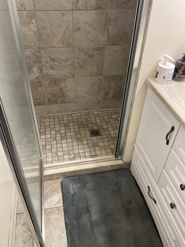 # Plumbing Service Completed

Responded to service call for clogged drain and backup issue in residential bathroom. Upon arrival, inspected both shower and bathtub fixtures to identify source of drainage problem. Assessed the walk-in shower with mosaic tile floor and center drain, as well as the adjacent bathtub with built-in drain and overflow system. Utilized appropriate drain clearing tools and techniques to remove obstruction from the affected drain line. Successfully restored proper water flow and drainage function to both fixtures. Tested system to verify complete resolution of backup issue and confirmed all drains operating normally.
