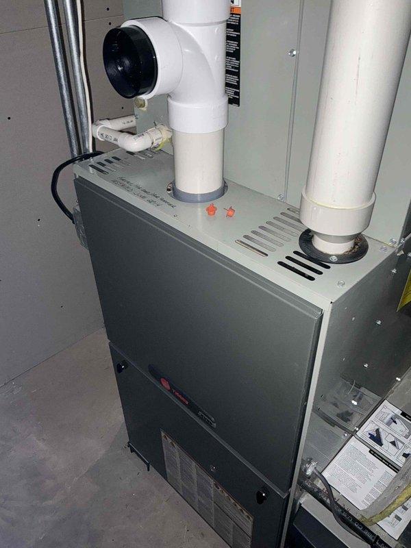 Completed comprehensive furnace tune-up during early morning service call. Performed thorough inspection of gray metal vertical cabinet-style HVAC furnace unit, including examination of ventilation system, PVC intake and exhaust piping, and electrical connections. Inspected and replaced air filter, ensuring proper mesh integrity and secure frame installation. Verified all mounting hardware, pipe connections, and safety indicators were functioning correctly. Unit found to be in clean, well-maintained condition with no visible signs of damage, corrosion, or operational concerns. All components tested and operating within manufacturer specifications upon completion of tune-up service.