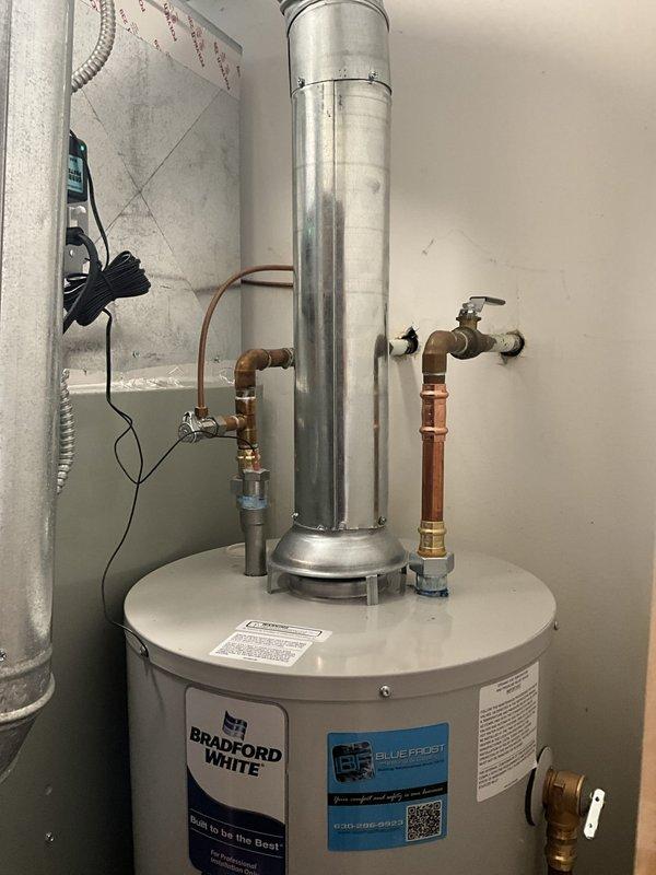 Completed same-day installation of Bradford White water heater in confined utility room space adjacent to existing Trane furnace. Removed old unit and installed new water heater with proper copper supply line connections, brass shut-off valves, pressure relief valve with discharge piping, and metallic exhaust venting. Ensured all plumbing connections were secured and tested for proper operation in the tight working area requiring two-person coordination for safe equipment placement and installation.
