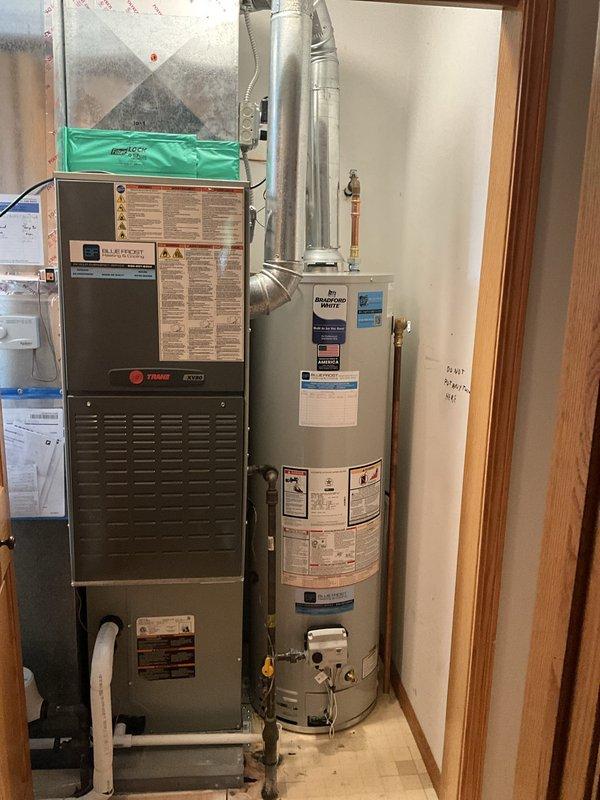 Completed same-day installation of Bradford White water heater in confined utility room space adjacent to existing Trane furnace. Removed old unit and installed new water heater with proper copper supply line connections, brass shut-off valves, pressure relief valve with discharge piping, and metallic exhaust venting. Ensured all plumbing connections were secured and tested for proper operation in the tight working area requiring two-person coordination for safe equipment placement and installation.