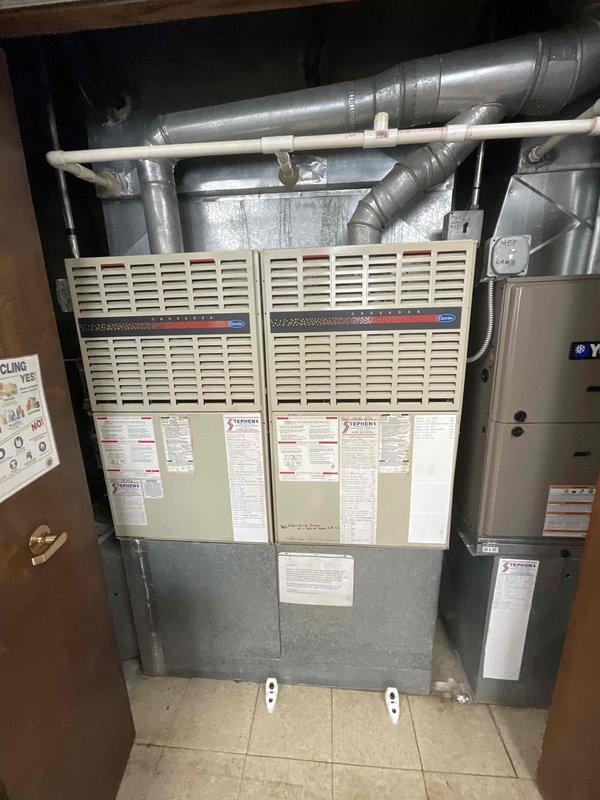 Conducted site assessment for commercial air conditioning and coil replacement estimate. Customer requested second opinion after another contractor recommended complete HVAC system replacement including furnaces. Inspected existing dual Carrier furnace installation located in utility room with side-by-side configuration. Evaluated ductwork system including horizontal metal supply ducts, flexible ductwork connections, and PVC condensate drain lines. Assessed confined space mechanical area beneath structural elements containing integrated HVAC and plumbing systems. Photographed existing equipment including furnace units with specification labels, galvanized metal plenum, gray ductwork, and water heater. Documented current system configuration to determine scope of work required for air conditioning and coil replacement without unnecessary furnace removal. Provided comprehensive evaluation to offer alternative solution focused specifically on AC and evaporator coil replacement needs.