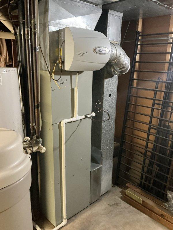 Completed installation of 10/7 combo HVAC system in residential basement, including new furnace unit and evaporator coil. Installed Aprilaire whole-house humidifier on top of furnace cabinet with proper ductwork connection to main supply plenum. Configured all refrigerant line sets, integrated ductwork with white insulated supply runs, and verified proper connection of gas lines with shut-off valves. System tested and operational.