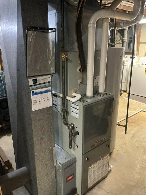 Completed installation of 10/7 combo HVAC system in residential basement, including new furnace unit and evaporator coil. Installed Aprilaire whole-house humidifier on top of furnace cabinet with proper ductwork connection to main supply plenum. Configured all refrigerant line sets, integrated ductwork with white insulated supply runs, and verified proper connection of gas lines with shut-off valves. System tested and operational.