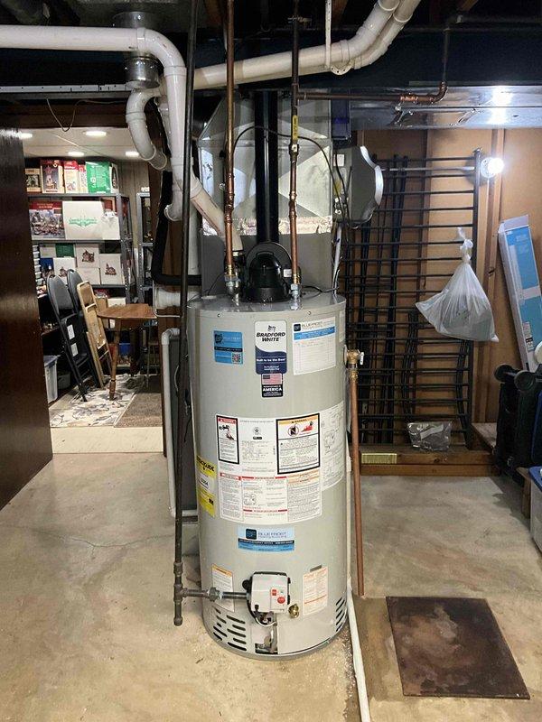 Removed and disposed of existing atmospheric venting water heater from basement utility area. Installed new 50-gallon natural gas power vent water heater with 6-year tank warranty. Drilled new exhaust penetration through right side exterior wall for power vent termination, installed beige PVC vent pipe with screened elbow cap, and sealed penetration with silicone. Installed electric anode rod to address iron content in water supply and extend tank lifespan. All copper supply lines and connections completed to manufacturer specifications.