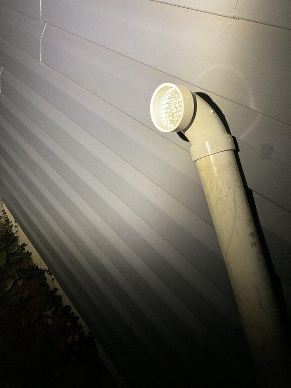 Removed and disposed of existing atmospheric venting water heater from basement utility area. Installed new 50-gallon natural gas power vent water heater with 6-year tank warranty. Drilled new exhaust penetration through right side exterior wall for power vent termination, installed beige PVC vent pipe with screened elbow cap, and sealed penetration with silicone. Installed electric anode rod to address iron content in water supply and extend tank lifespan. All copper supply lines and connections completed to manufacturer specifications.