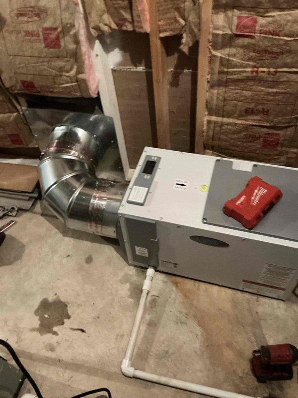 Reconnected E100 dehumidifier to existing ductwork configuration per customer request. Utilized existing duct run from previous dehumidifier installation to connect to first floor HVAC unit in basement utility area. Modified installation plan from original system integration to standalone ducting arrangement based on customer preference change.