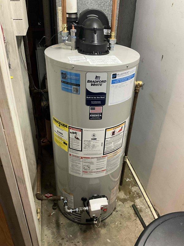 Completed installation of Bradford White residential tanked water heater in basement utility area. Unit was positioned on concrete floor with proper clearances, connected all copper supply and discharge piping, installed temperature and pressure relief valve with drain line, and secured all plumbing connections with shut-off valves. Verified proper venting through flue hat assembly and confirmed all manufacturer safety labels and specifications are visible and intact per code requirements.