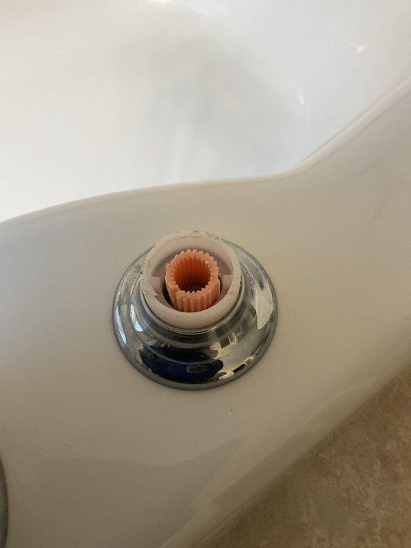 Responded to a reported bathtub leak and inspected the fixture, finding the handle removed and the escutcheon, valve cartridge housing, and splined stem exposed with visible wear at the housing rim. Accessed the valve assembly to diagnose the leak source, and the ceiling light fixture below was found disconnected from its mounting plate and hanging by its wires from the junction box, likely due to water intrusion or access work.