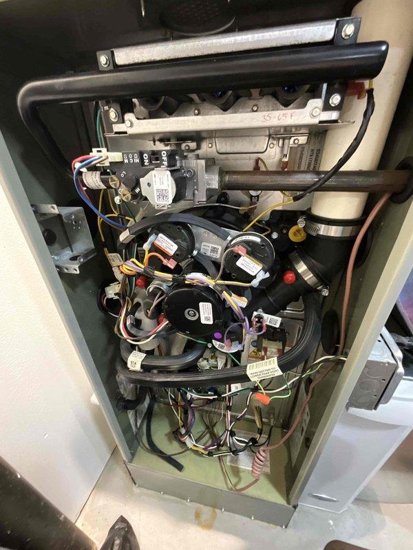 Performed a complete tune-up on an 8-year-old gas furnace, inspecting the burner assembly, gas valve, inducer motor, pressure switches, PVC vent connections, and wiring harness for proper operation. Inspected the igniter and flame sensor assembly, noting soot staining and light rust residue at the burner opening, and verified secure mounting hardware. Equipment was found operational with no frost or heavy corrosion present, and the unit was enrolled in a recurring furnace maintenance plan.