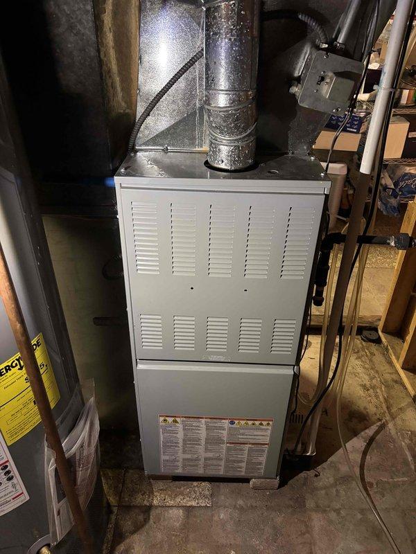 Performed a seasonal heating tune-up on an upright gas furnace, including inspection of the burner assembly and verification of normal ignition with a stable blue flame. Used a true RMS clamp meter to check electrical readings, and inspected the flue vent piping, condensate drain, and surrounding cabinet and connections for proper operation. The unit showed no signs of heavy rust or major damage and was left operating normally.