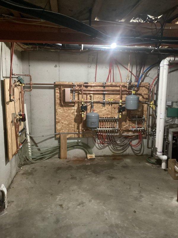 Completed installation of new hydronic heating system with multiple zones, including removal of old piping, installation of three supply manifolds, plate-to-plate heat exchanger for wood boiler integration, and four supply pumps for in-floor heating. System was completed with new air separator, expansion tank, fill valve, and appropriate antifreeze for the wood boiler and in-floor tubing components.