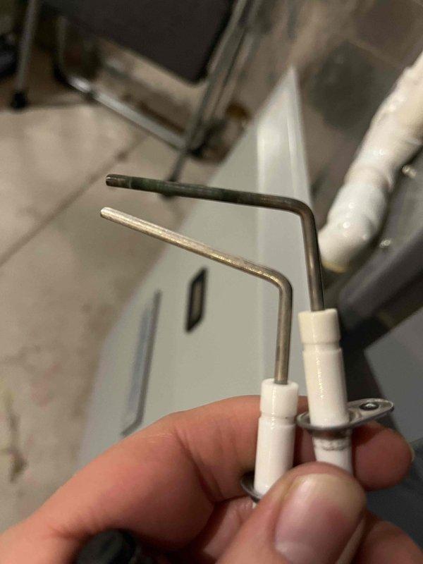 Sold repair for flame sensor replacement. Removed heavily degraded flame sensor from heating system showing compromised combustion operation, as evidenced by visible flame pattern through inspection port. Installed new flame sensor, restoring proper flame detection capability to ensure reliable system operation.