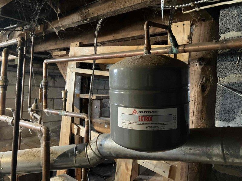 Responded to service call regarding water leakage from boiler exhaust. Diagnosis revealed failed Amtrol Extrol expansion tank causing water leakage. Replaced defective expansion tank and additional compromised components to restore proper system operation and prevent further leakage.