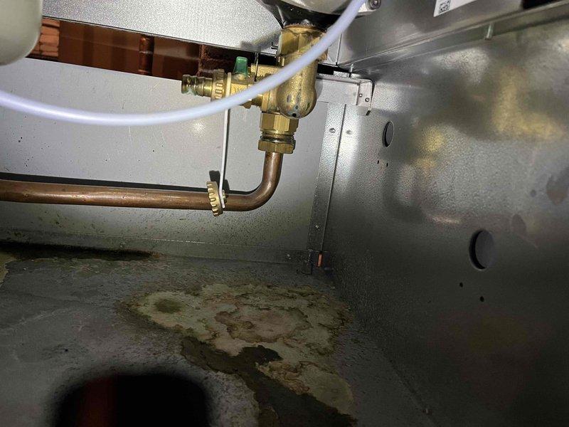 Responded to service call for a leaking boiler. Inspection revealed seeping gaskets at the manifold with visible water damage and mineral deposits. Presented repair estimate to customer for replacement of deteriorated components.