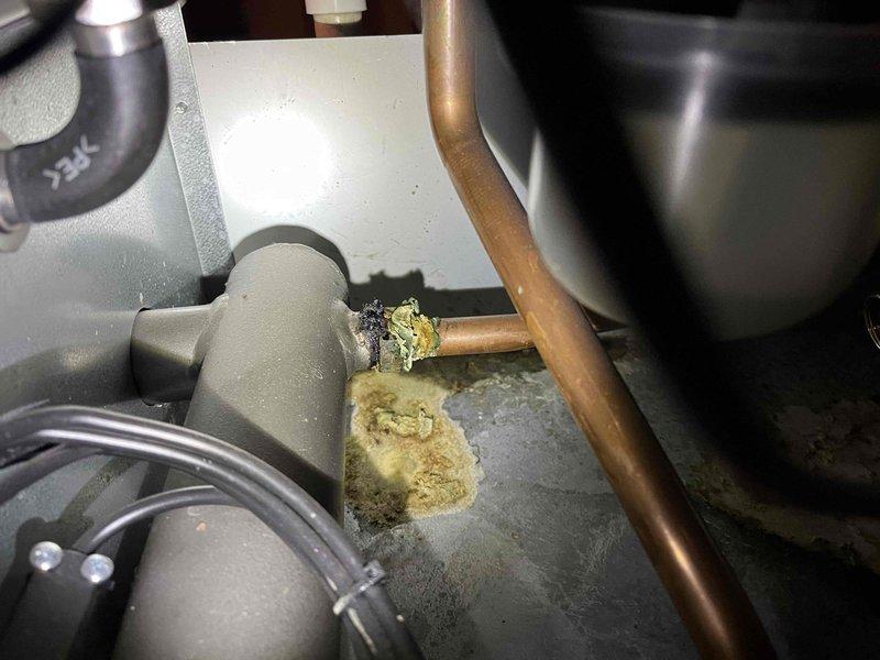 Responded to service call for a leaking boiler. Inspection revealed seeping gaskets at the manifold with visible water damage and mineral deposits. Presented repair estimate to customer for replacement of deteriorated components.