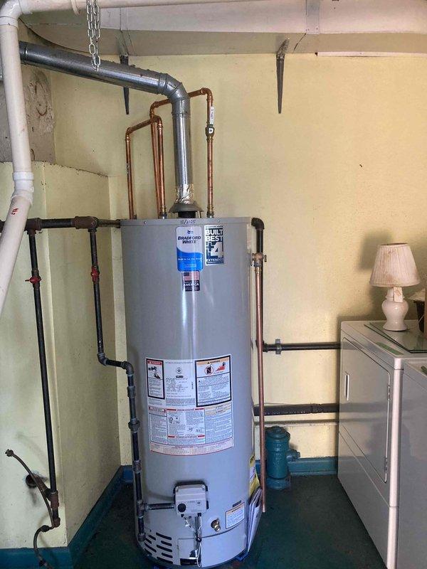 Successfully installed a Bradford White 50-gallon natural draft water heater in basement utility area. Completed all necessary plumbing connections with copper and black pipes, including proper venting with metal exhaust pipe. Installation includes manufacturer's 6-year parts and tank warranty with 1-year labor coverage.
