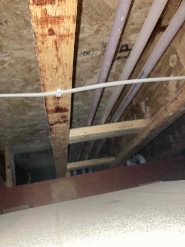 Performed diagnostic assessment on 18-year-old tankless water heater experiencing intermittent hot water delivery issues. System was operational but not distributing hot water consistently to required locations. Conducted thorough cleaning of unit components to improve performance. Noted structural conditions in surrounding area, including evidence of moisture exposure on wooden joists and existing PVC plumbing configuration.