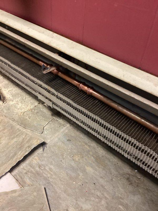 Replaced two deteriorated zone valve assemblies and rewired them to transformer and end switch, bypassing the existing controller. Repaired splits in baseboard heating system and purged the system to address active leaks. Inspection of the recessed access panel revealed significant moisture damage and debris accumulation around the copper supply lines, which were successfully remediated during the repair process.