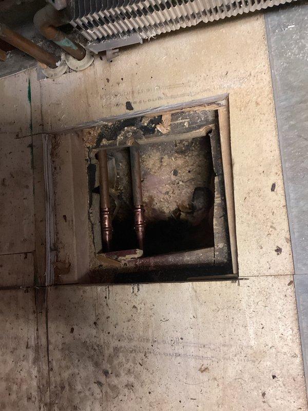 Replaced two deteriorated zone valve assemblies and rewired them to transformer and end switch, bypassing the existing controller. Repaired splits in baseboard heating system and purged the system to address active leaks. Inspection of the recessed access panel revealed significant moisture damage and debris accumulation around the copper supply lines, which were successfully remediated during the repair process.