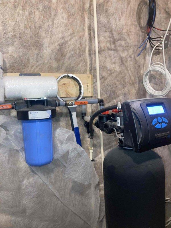 Completed annual prepaid preventative maintenance on residential water treatment system, including inspection of water heater, blue WELL-X-TROL pressure tank, and water filtration components. Verified proper operation of water softener unit with digital control panel and confirmed all connections, valves, and pressure readings were within normal operating parameters.